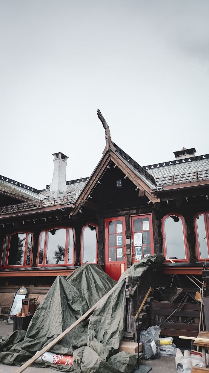 A traditional wooden house with a steep gabled roof undergoing renovation.